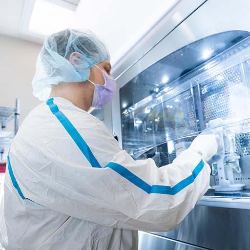 A technician works with automation equipment to prepare an IV solution.