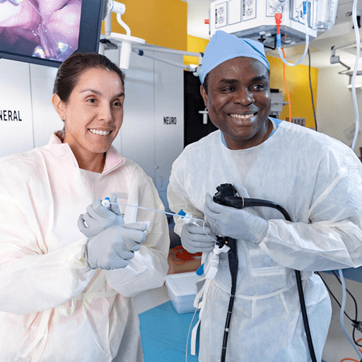 Two fellows in lab coats and gloves working with equipment