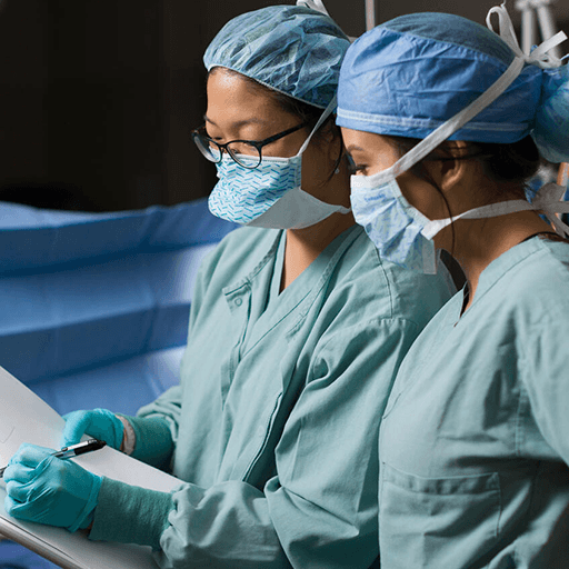 Two anesthesiology residents in operating room looking at a chart