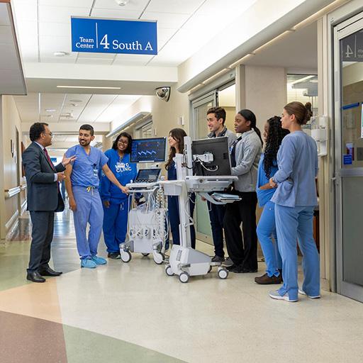 Eight people from the Critical Care Medicine Fellowship program at Mayo Clinic in Jacksonville, Florida, had a discussion around two monitors in a hallway.
