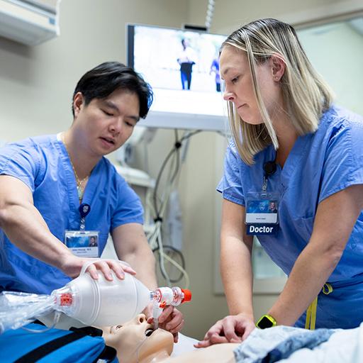 Two doctors practice a procedure in an operating room.