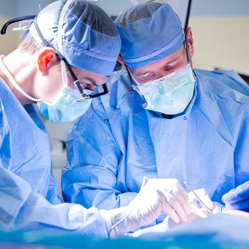 Two doctors in scrubs perform a surgery.