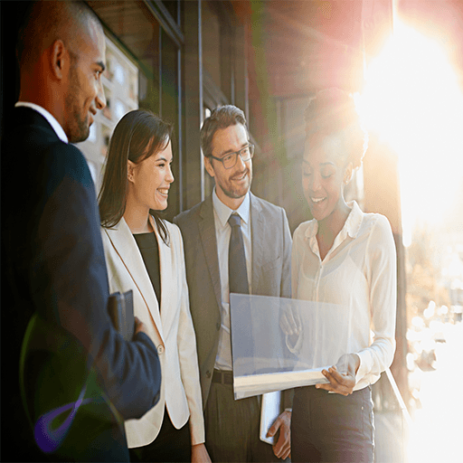 A group of professionals looking at a screen smiling with the bright son behind them.
