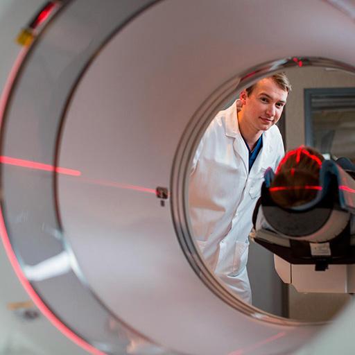 Nuclear medicine technologist assists a patient with a procedure