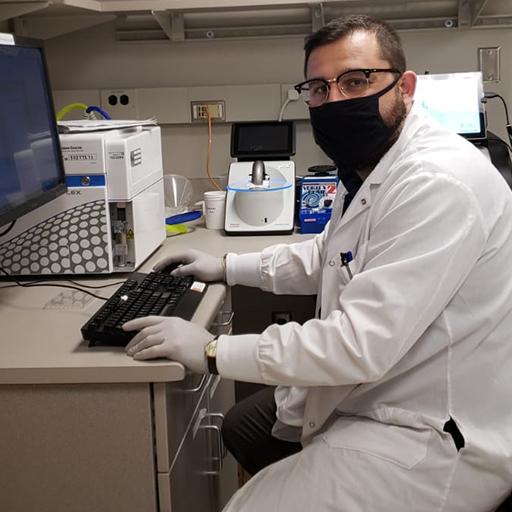 Ismail Can, Ph.D. student typing at computer in his research lab
