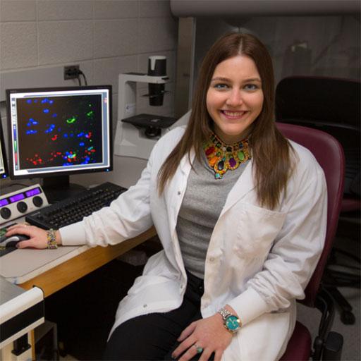 Luz Cumba-Garcia sitting at her desk and computer looking at the camera