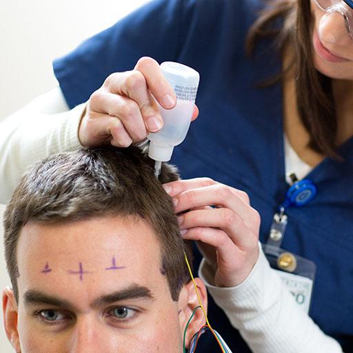A student in clinical neurophysiology technology prepping a patient for a sleep study