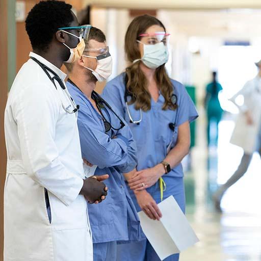 Physician speaks with fellows in a hospital hallway at Mayo Clinic