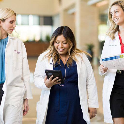 Three fellows standing in hallway looking at tablet