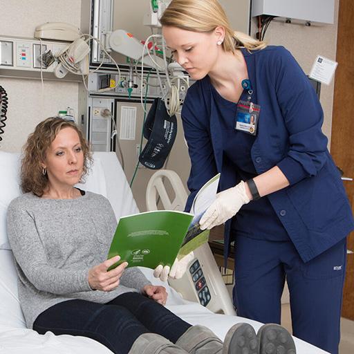 An RN specialized in cancer care shows materials to a patient in an exam room