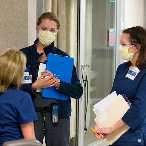 Staff RN Case Manager discussing patient cases in hallway of hospital