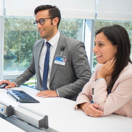 Dr. Lopez consults with fellows at a white table in a conference room with a scan of a brain on a screen beside them.