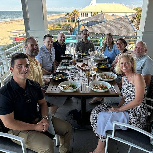 Nine people from the Cardiothoracic Imaging Fellowship program gathered for an outdoor dining experience overlooking the beach.