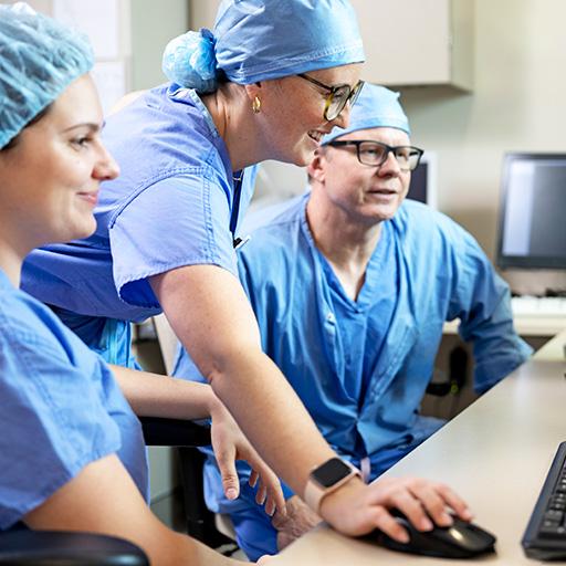 Three people looked at a computer monitor while one person used the computer mouse to highlight information.