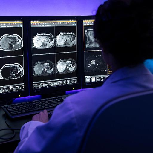 A doctor reviews scans on computer monitors.