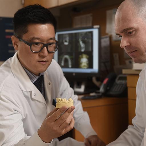 Faculty member from the Periodontics Residency at Mayo Clinic in Rochester, Minnesota, uses a model of a jaw while speaking with a resident.