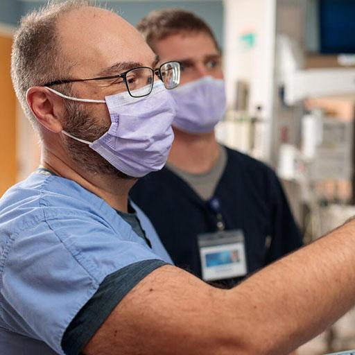 Neurology physician and resident look at a brain activity scan on a computer monitor