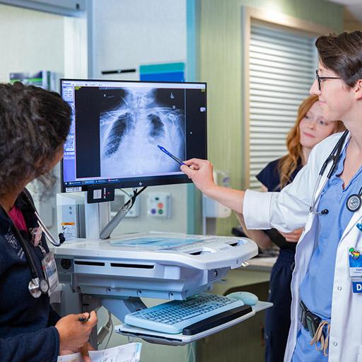 Pulmonary and Critical Care Medicine fellows and faculty talking in the hallway looking at a scan on a computer at Mayo Clinic in Rochester, Minnesota.