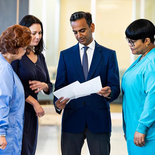 Division of Surgical Oncology staff stand together in a corridor and review information on documents