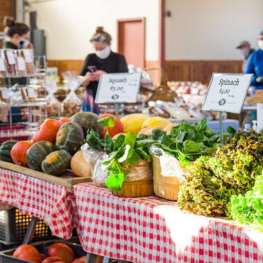 Table display with spinach and pumpkins piled high at the farmers market
