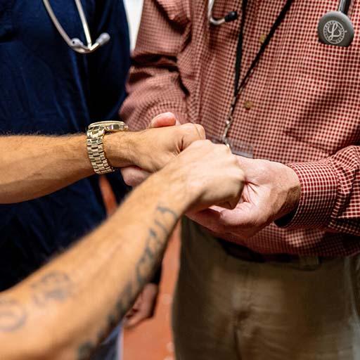 A doctor and medical students examine a young man’s hand while working in a community outreach program