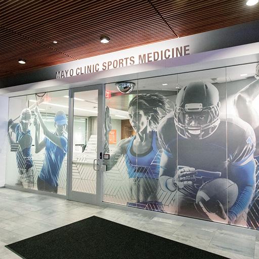 Glass wall mural of athlete images inside of Mayo Clinic Square building in Minneapolis, MN.