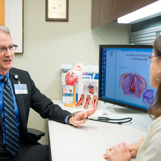 Dr. Burger and a patient have a conversation sitting at a desk in an office