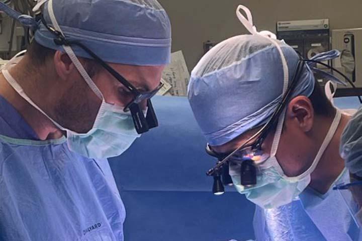 Two surgeons look down towards a patient during a procedure.