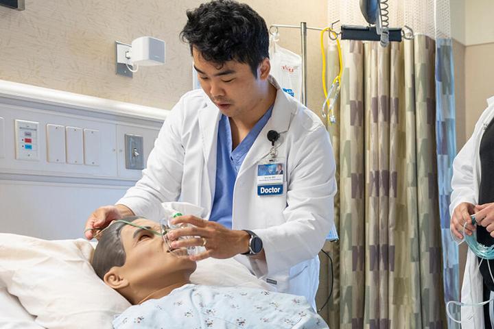 A resident places a breathing mask on a medical mannequin during the Anesthesiology Resident simulation center workshop.