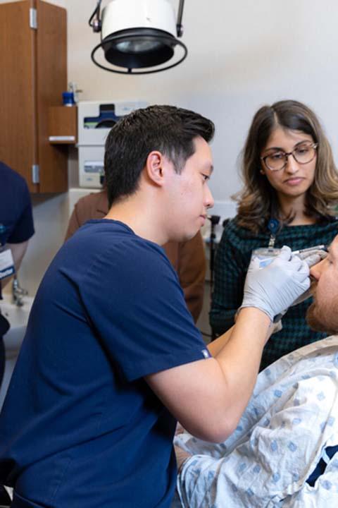 Hafsa Cantwell, MD, Dermatology consultant, guides a Dermatology resident in a cosmetic injection practice session while others observe.