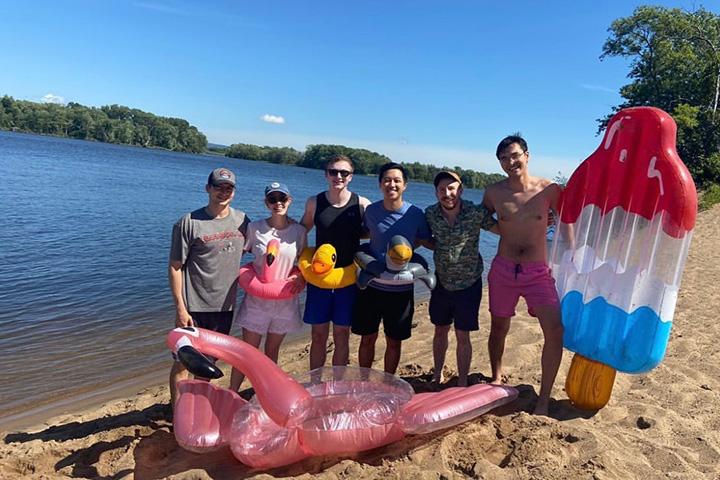 Six residents wearing duck floaties and surrounded by other floatables gathered for a photo on the beach.