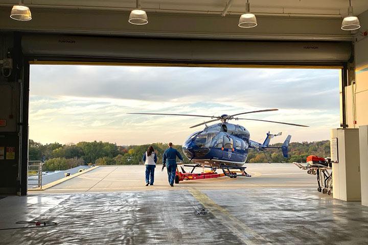 Mayo Clinic physicians walk out to the Mayo One helicopter waiting on the ground in the hanger