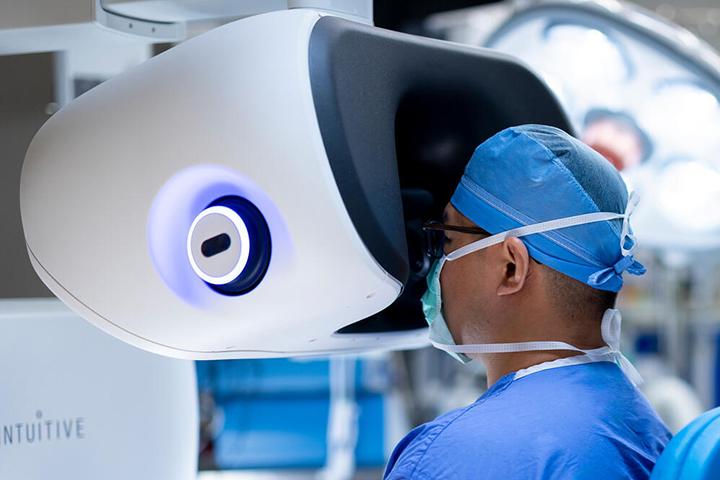 A doctor looks through a machine during a procedure in an operating room.