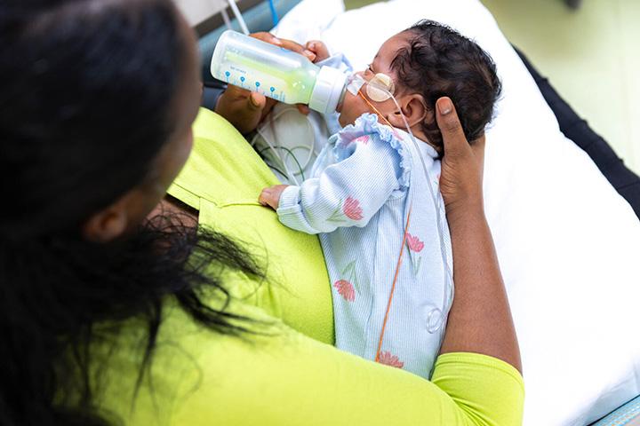A newborn baby is given a bottle in the NICU.