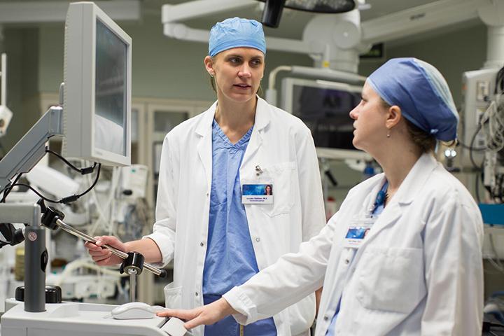 Two surgeons from the Rhinology and Skull Base Surgery Fellowship talk in an operating room.