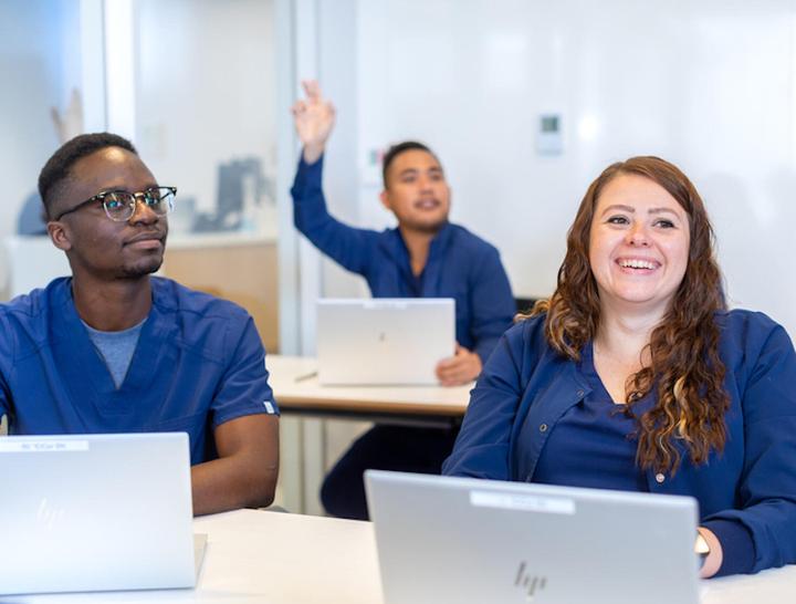 Three students smiling in class setting