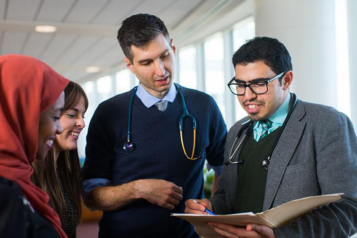 Four residents at Mayo Clinic grouped together, looking over paperwork in a folder