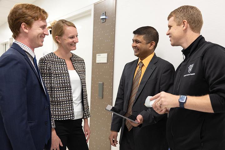 Four fellows standing in the hall discussing something