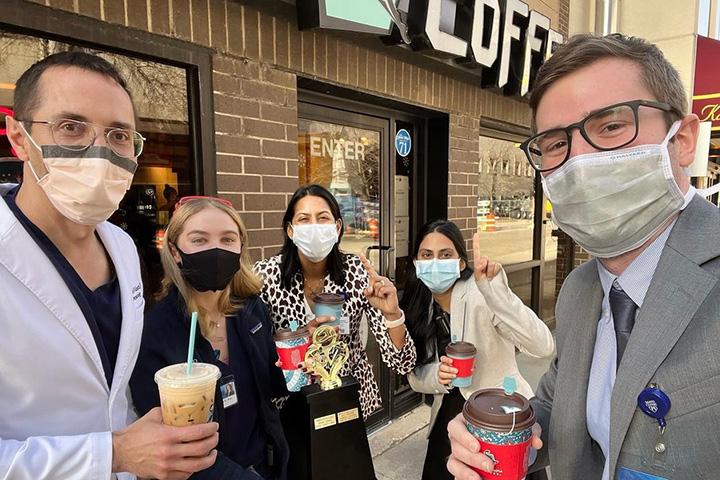 Five residents took a group selfie while holding to-go drinks in front of a local coffee shop.