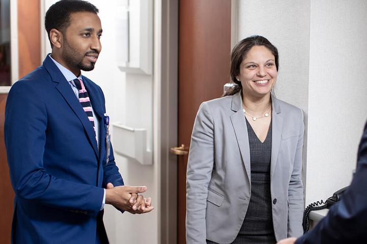 Three doctors have a discussion in a clinic hallway.