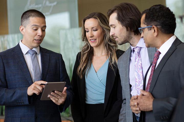 Infectious disease fellows and physicians gather around to look at a tablet in a lobby at Mayo Clinic.