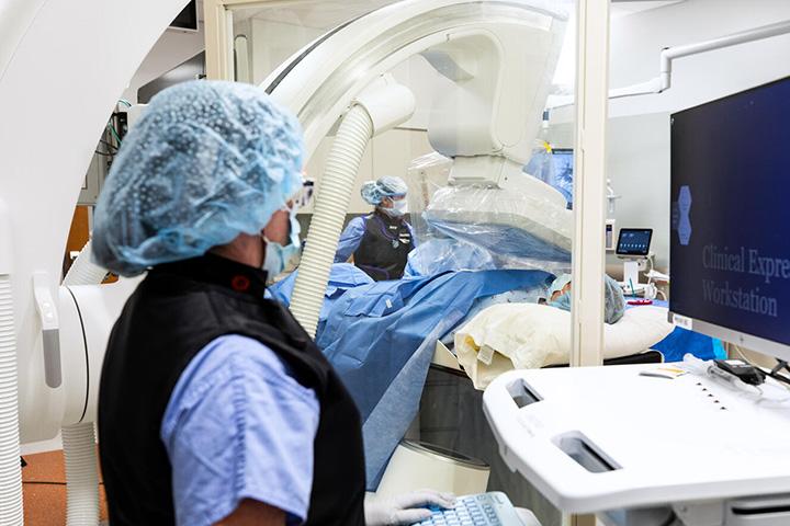 One doctor observing another doctor performing a procedure on a patient.