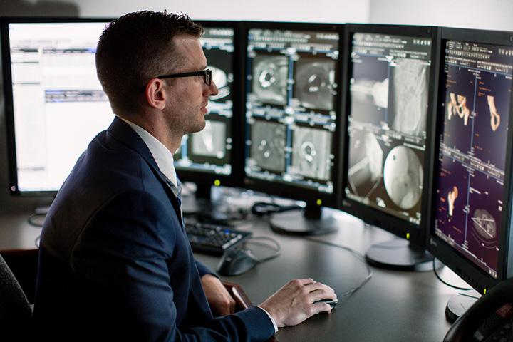 Trainee working at computer desk looking at x-rays.
