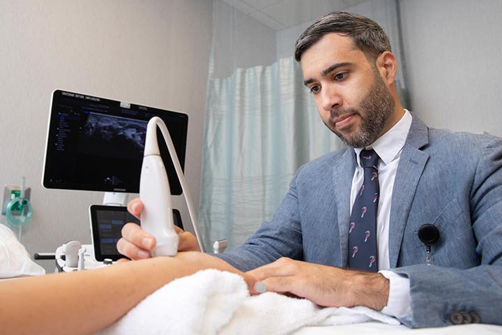Physical Medicine and Rehabilitation Residency doctor performs an ankle ultrasound in an exam room.