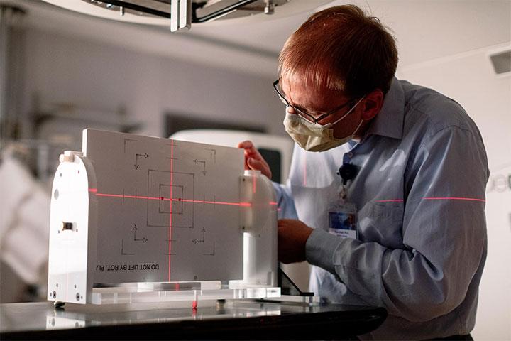 A Mayo Clinic radiation oncology medical physicist inspects a piece of equipment.