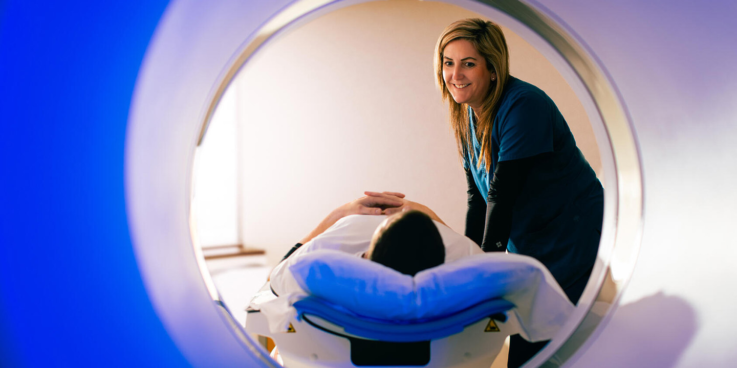 A radiology imaging technologist assists a patient with image scanning equipment