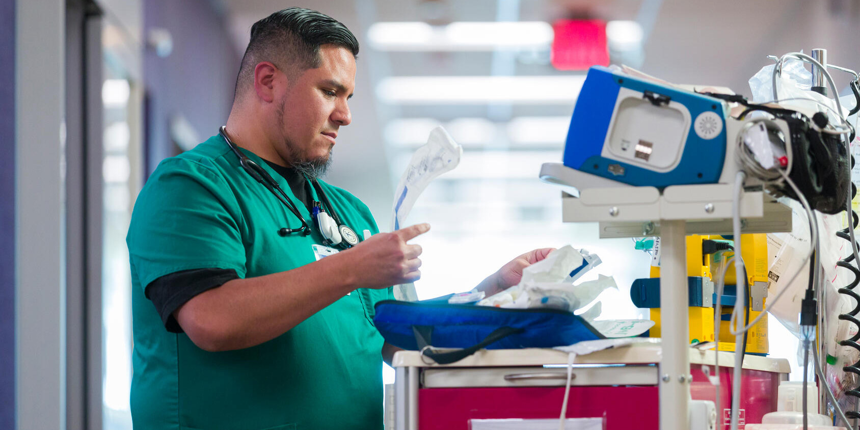 Respiratory therapy practitioner organizes equipment on a cart in the hospital